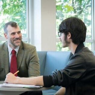 Assistant Professor of History David Kieran, Ph.D., talks with students in the Clark Family Library.